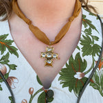 Bronze scarf-style necklace with knotted details and gold cross pendant accented with gemstones.