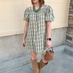 Light olive smocked mini dress with tonal floral print, puff sleeves, and square neckline