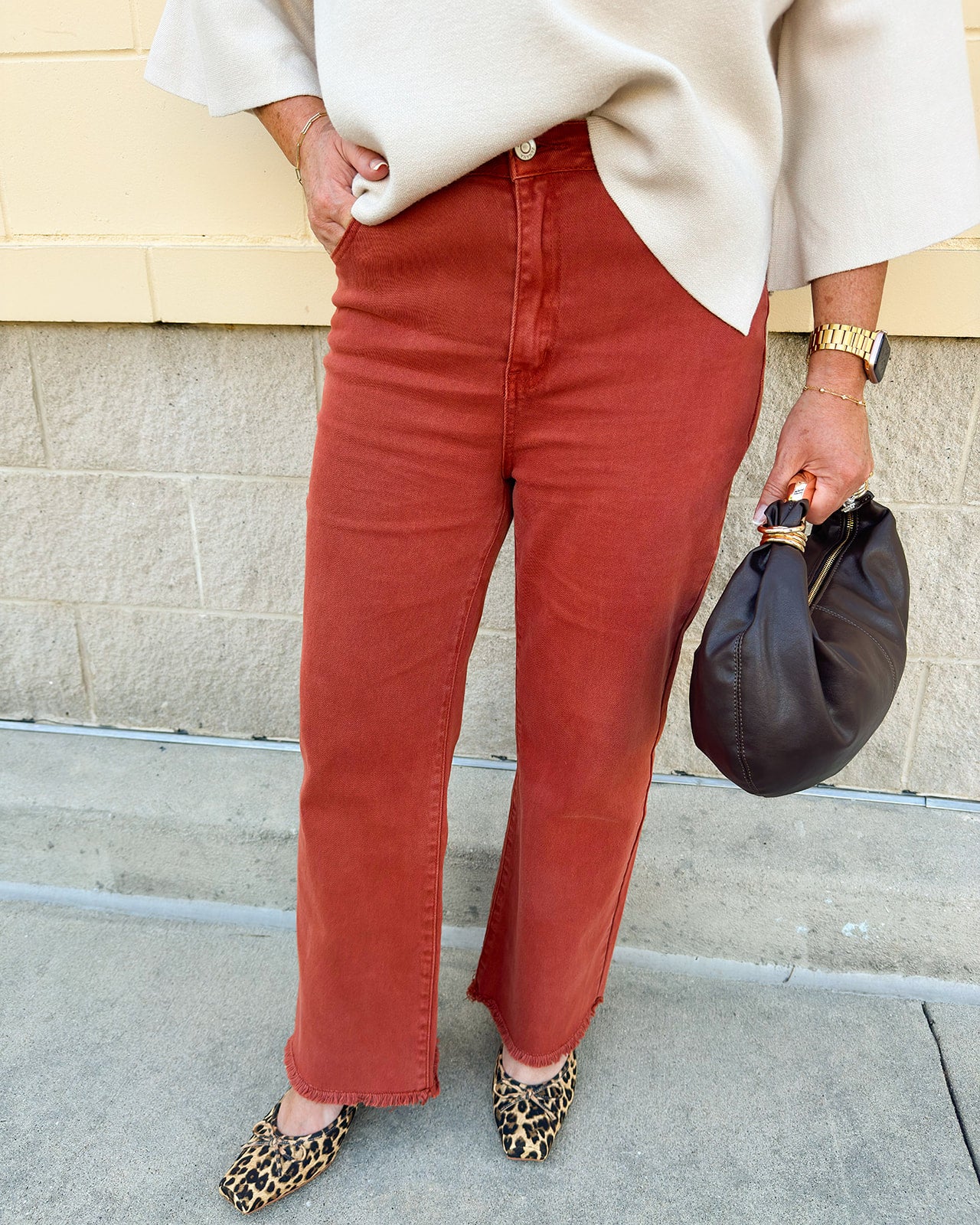Rust acid-washed high-waisted bootcut pants with frayed hem.