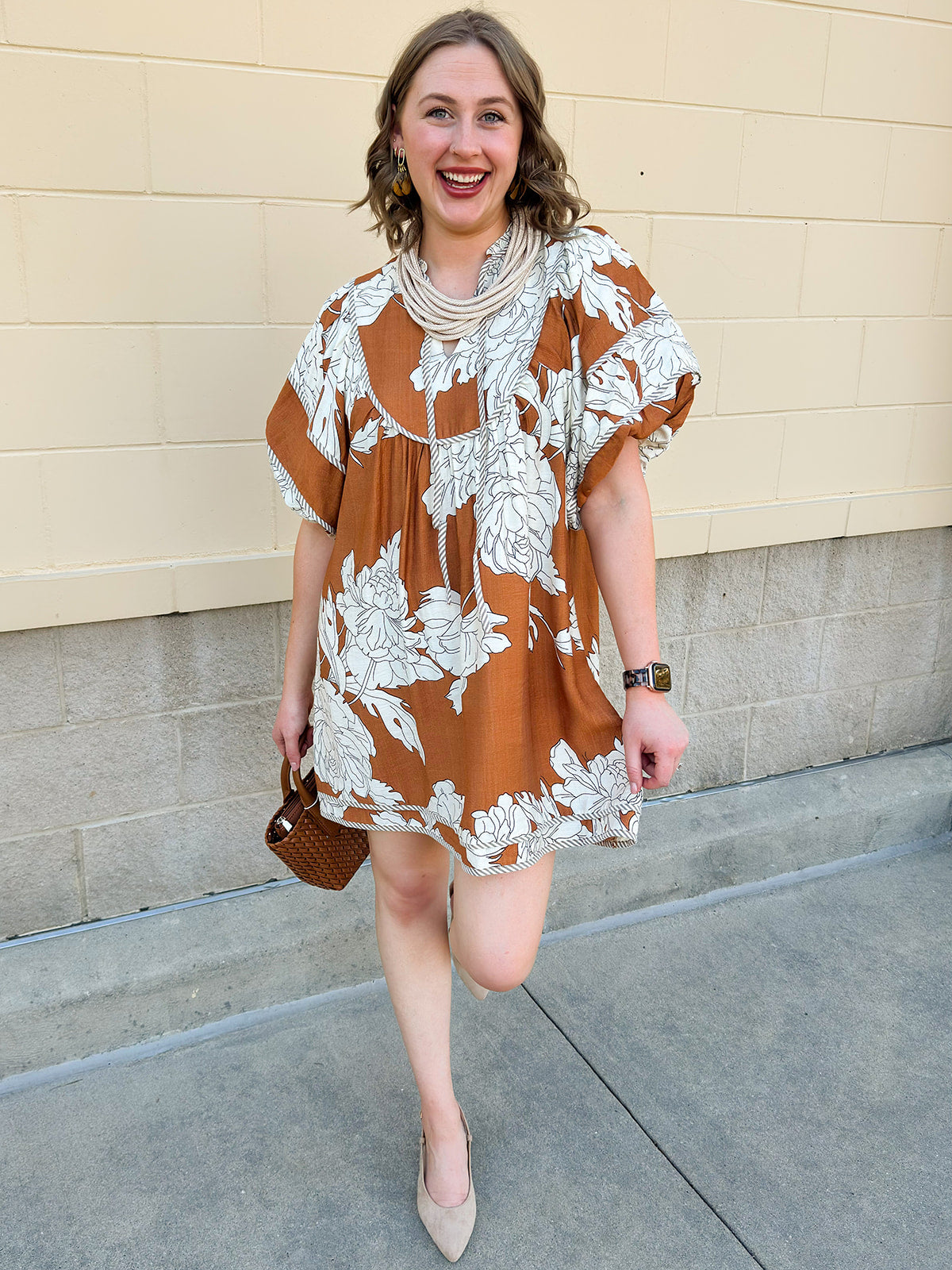 Bronze and cream babydoll mini dress with ruffled neckline, puff sleeves, and striped piping detail.