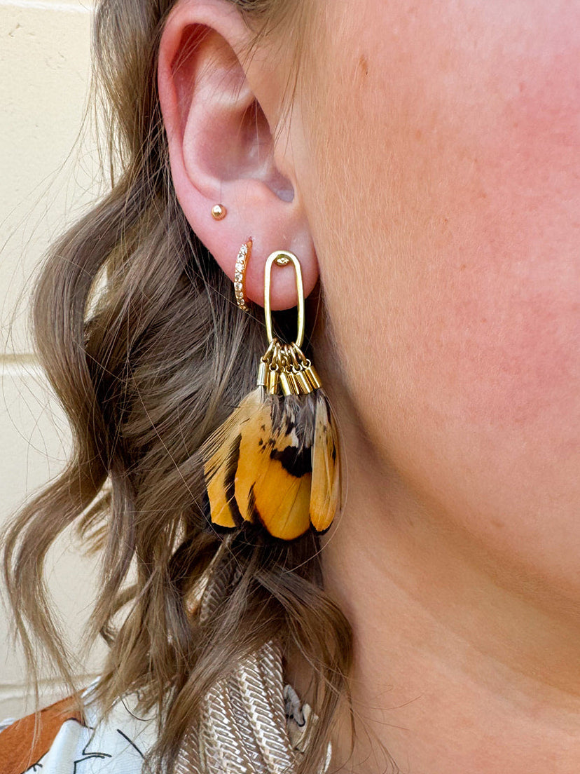 Quail feather tassel statement earrings with speckled feathers and soft tassels, displayed on a neutral background