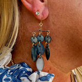 A pair of dangling mobile art shell earrings with various shades of blue and gold tones.