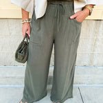Olive wide-leg linen pants with drawstring waist, cropped length, and frayed hem.