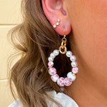 A pair of floral ceramic hoop earrings with pink, featuring hand-painted ceramic beads, glass pearls, and gold-tone accents.