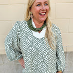 Sage and cream boho leaf print top with 3/4 sleeves, standing collar, lace trim, and solid contrast detail.