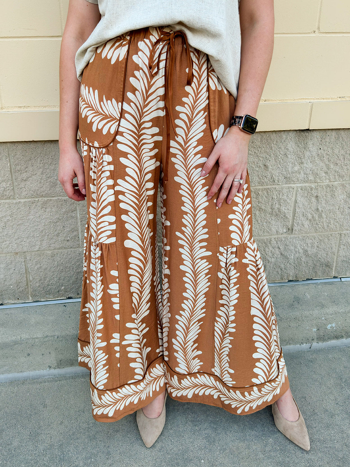 Clay and cream wide-leg pants with elastic waistband, pleating details, and side pockets.