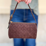 Chocolate brown cylinder-shaped shoulder bag with adjustable buckle strap and zip closure.