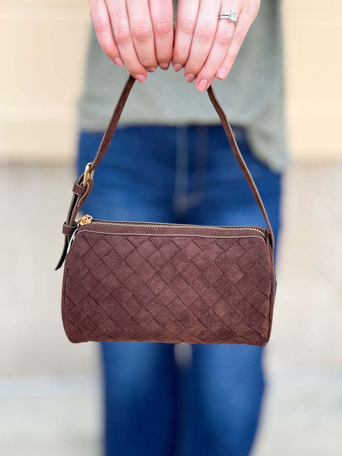 Chocolate brown cylinder-shaped shoulder bag with adjustable buckle strap and zip closure.