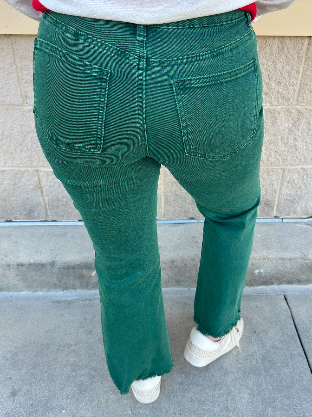 Emerald green high-waisted bootcut pants with a subtle flare and frayed hem.