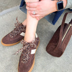 Chocolate suede low-top sneakers with cream detailing, leopard print laces, and rubber soles.