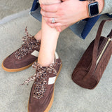 Chocolate suede low-top sneakers with cream detailing, leopard print laces, and rubber soles.