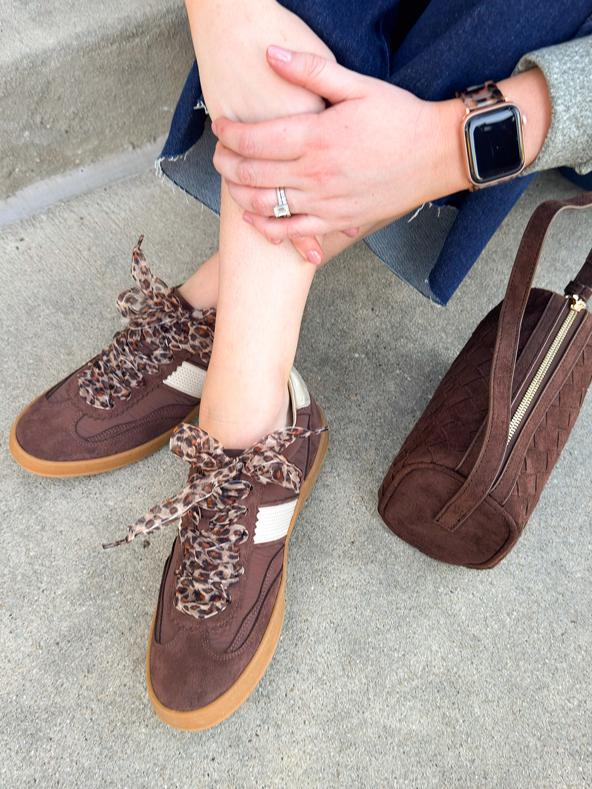 Chocolate suede low-top sneakers with cream detailing, leopard print laces, and rubber soles.