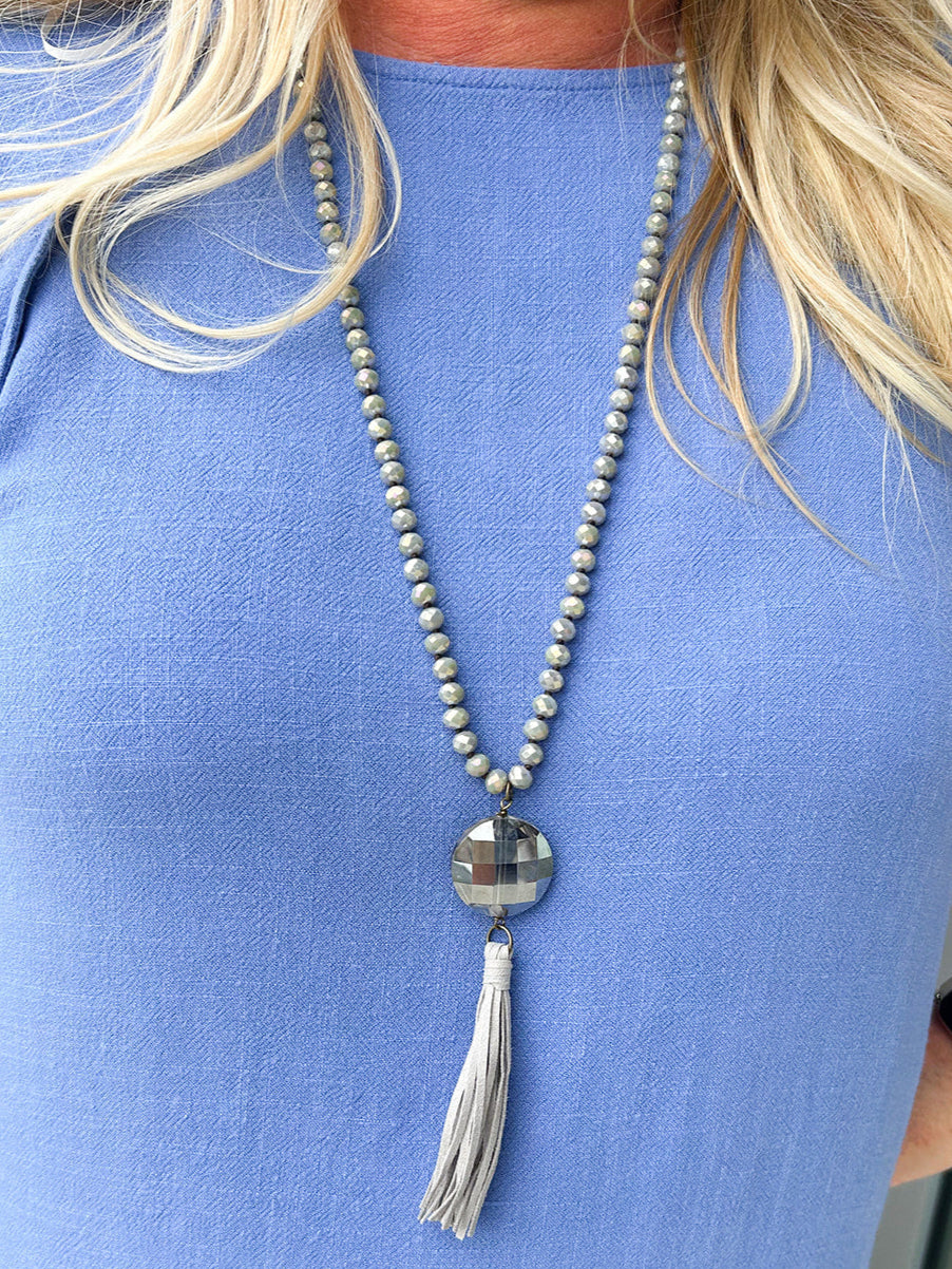 Gray crystal bead necklace with long leather tassel pendant.