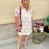 Cream mini dress with taupe geometric eyelet pattern, puffed sleeves, open collar, and side pockets