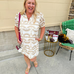 Cream mini dress with taupe geometric eyelet pattern, puffed sleeves, open collar, and side pockets