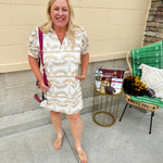 Cream mini dress with taupe geometric eyelet pattern, puffed sleeves, open collar, and side pockets