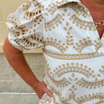 Cream mini dress with taupe geometric eyelet pattern, puffed sleeves, open collar, and side pockets
