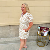 Cream mini dress with taupe geometric eyelet pattern, puffed sleeves, open collar, and side pockets