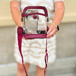 Garnet-trimmed clear stadium bag with zipper closure, top handle, and adjustable crossbody strap.