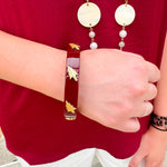 Garnet resin bangle with gold FSU logo charm on a white background