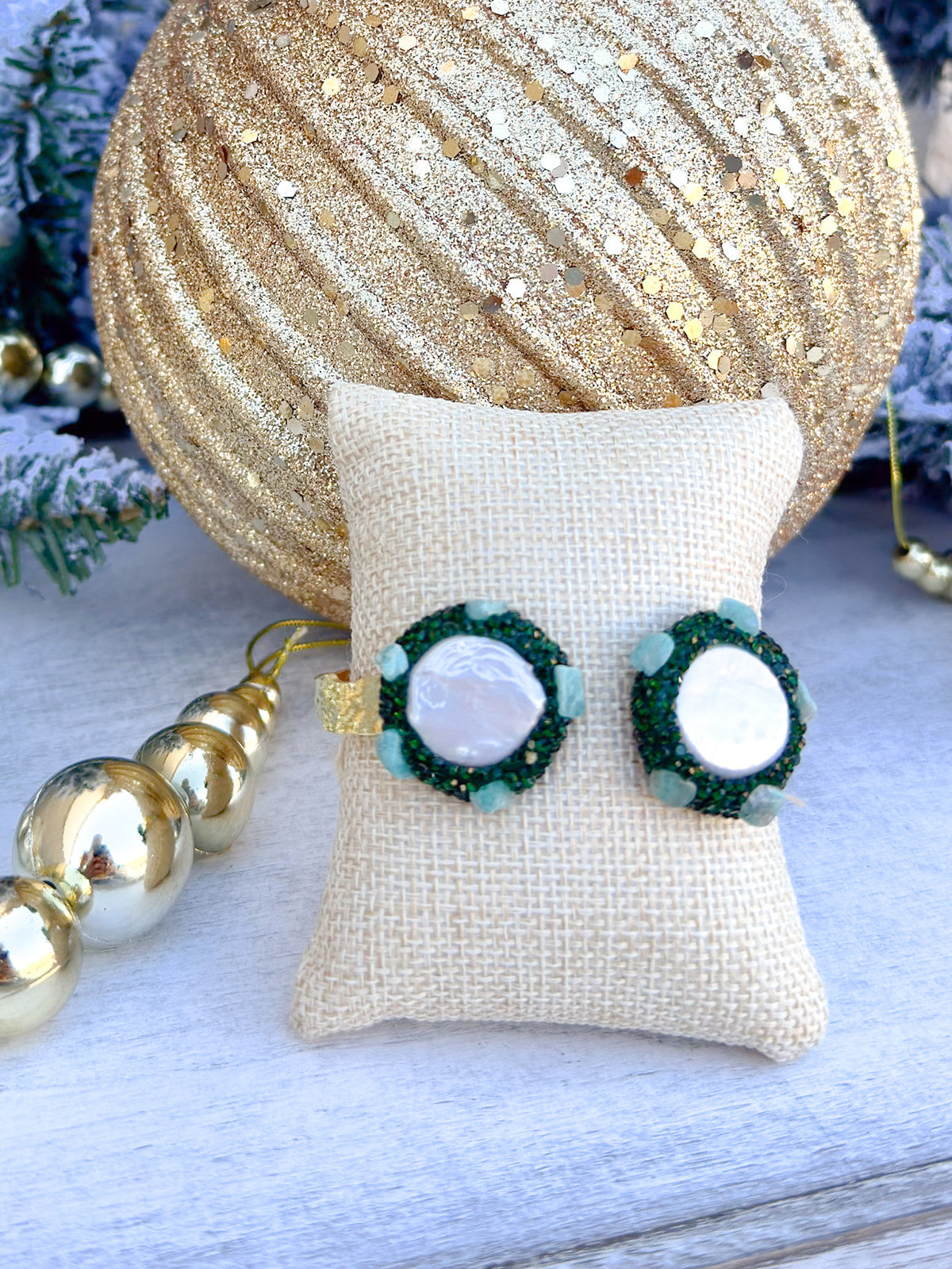 Gold cuff bracelet with freshwater pearls on each end surrounded by green gemstones, handmade by Easton Elle.