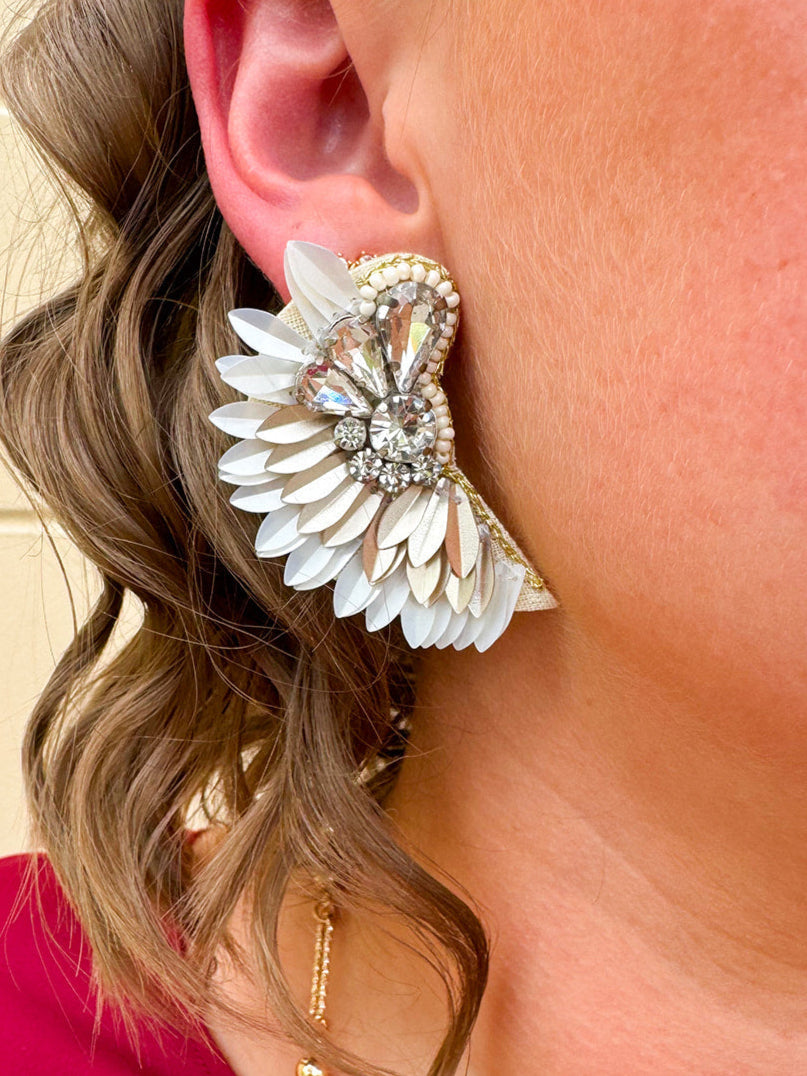 Gold and white feather-inspired earrings with a folded design and silver rhinestone cluster at the stud—lightweight with a bold, elegant look.