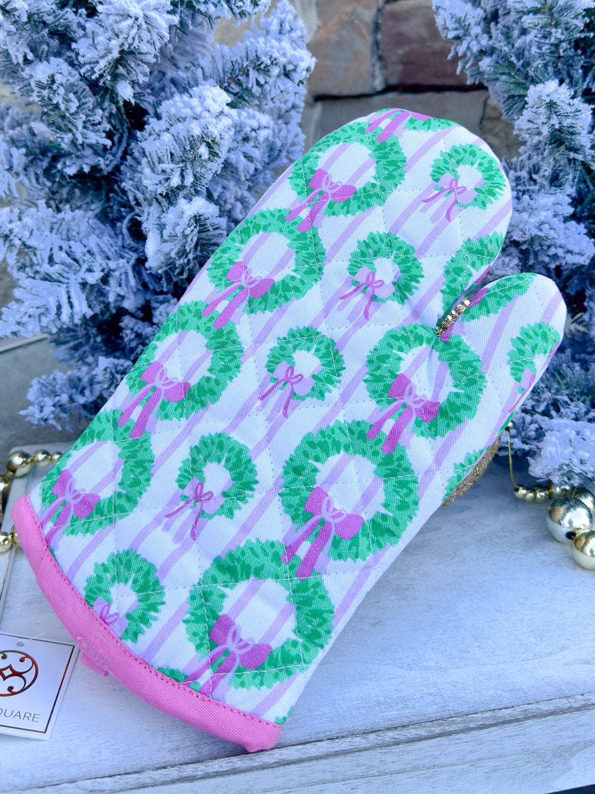 White oven mitt with green wreath and pink bow pattern, pink piping trim.