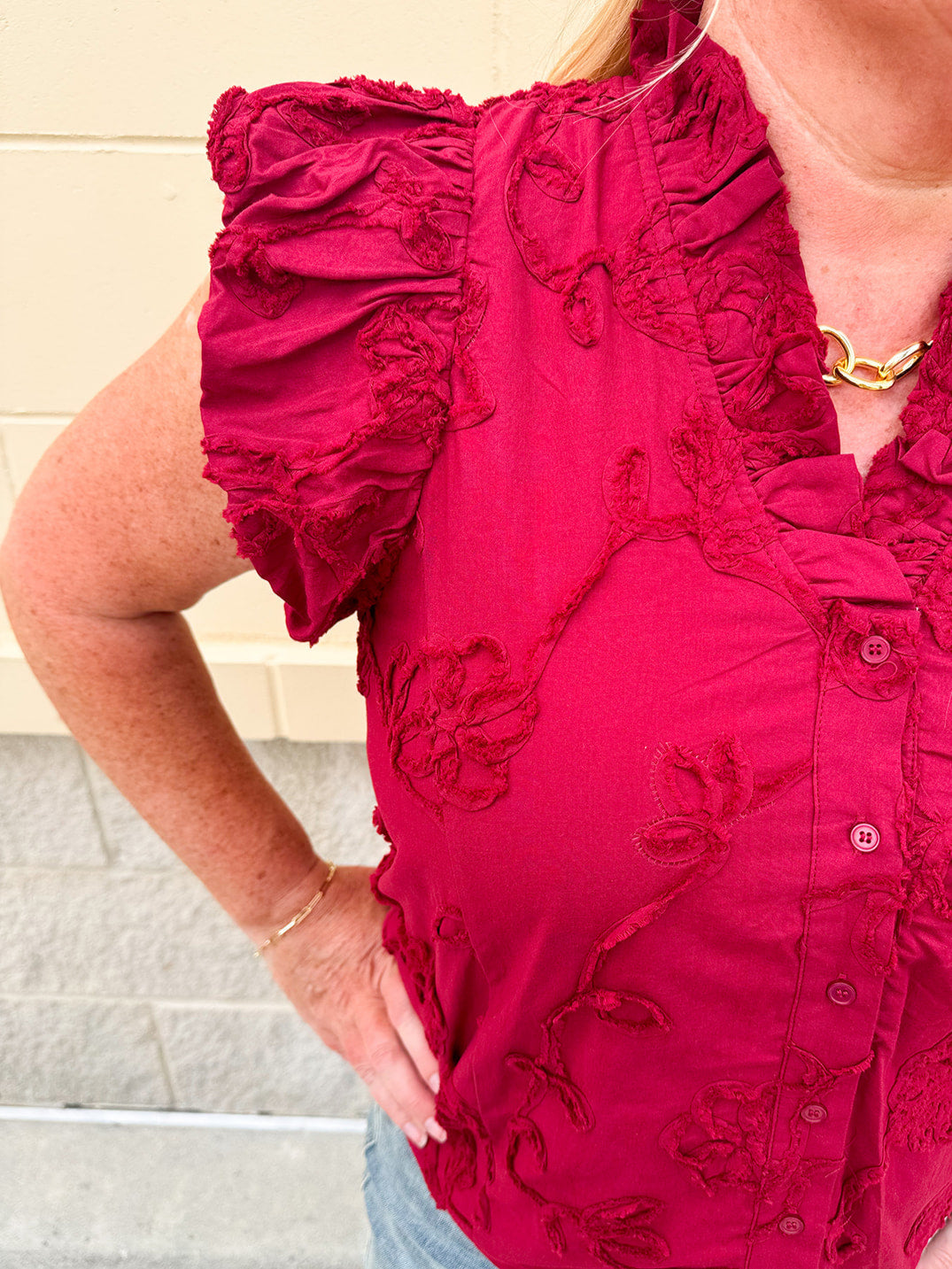 Garnet cotton flutter sleeve top with floral appliqué, ruffle V-neck, and button front—lightweight and perfect for gameday