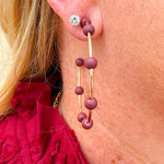 Gold hoop earrings with maroon-coated metal bead accents, offering a bold yet elegant pop of color.