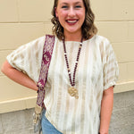 Cream and gold striped round-neck top with dolman sleeves and elastic cuffs, styled for summer.