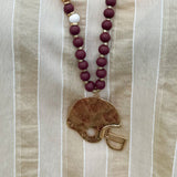 Statement necklace with garnet, white, and gold beads featuring a hammered gold football helmet pendant—perfect for spirited Gameday wear.