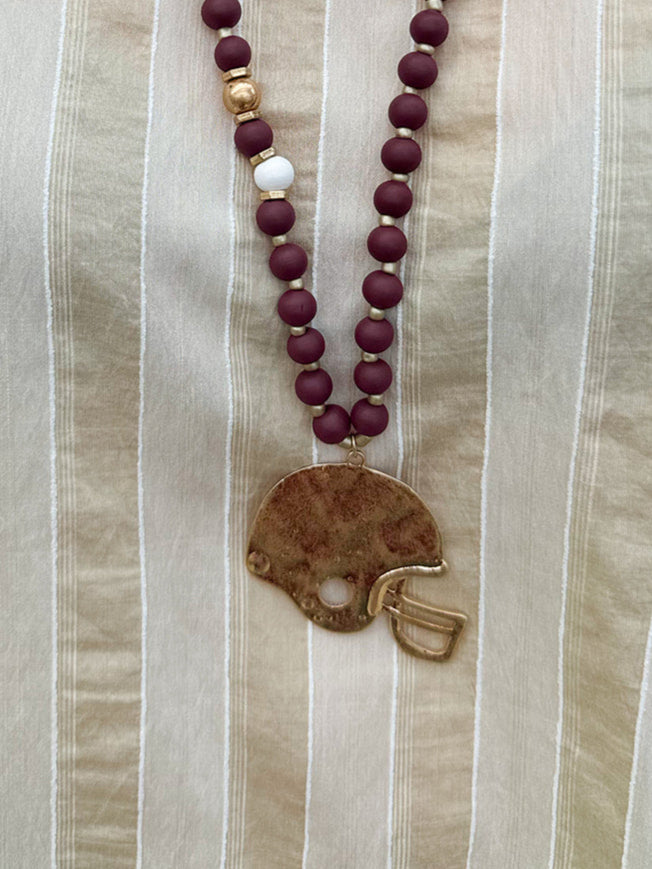 Statement necklace with garnet, white, and gold beads featuring a hammered gold football helmet pendant—perfect for spirited Gameday wear.