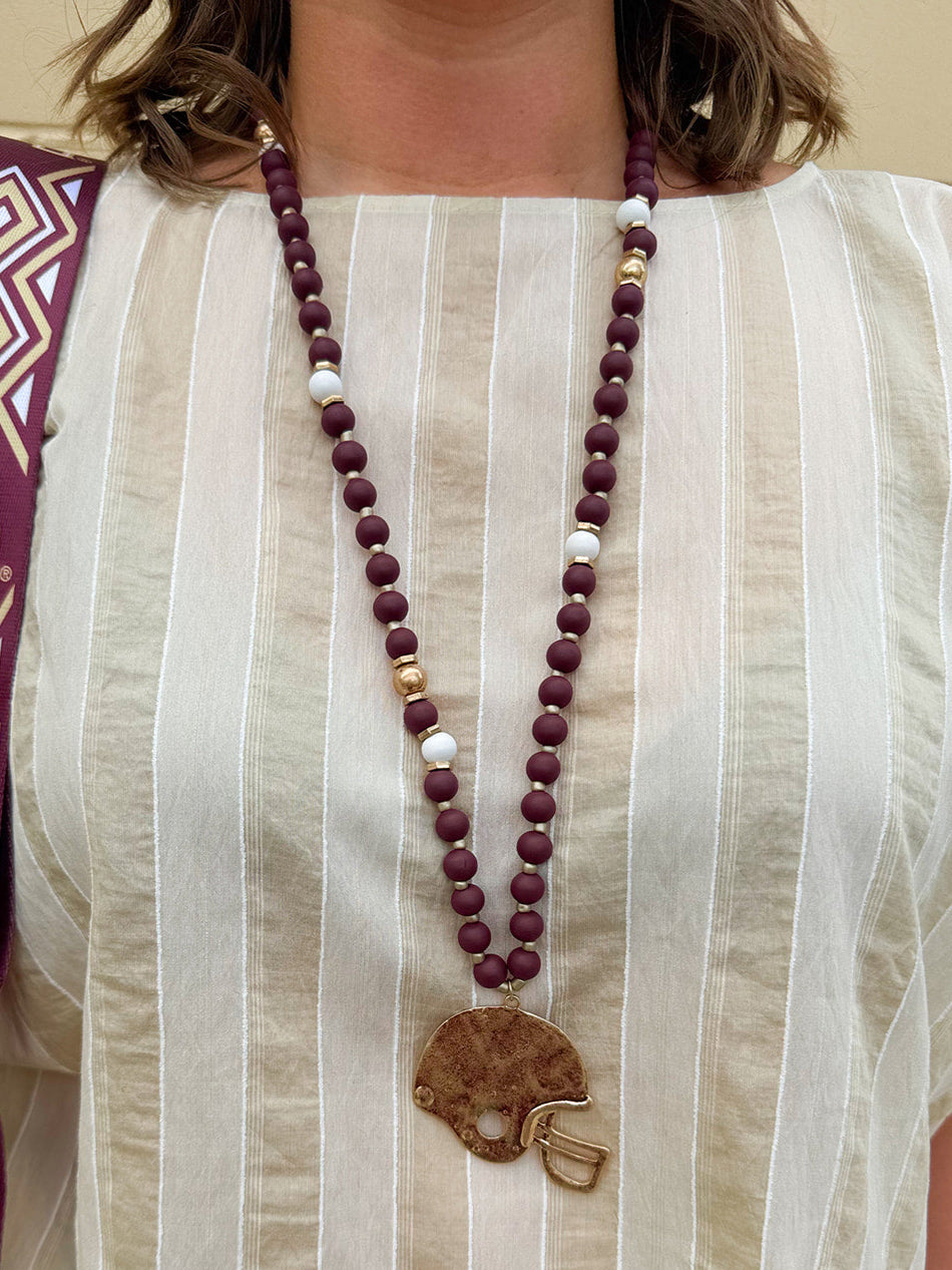 Statement necklace with garnet, white, and gold beads featuring a hammered gold football helmet pendant—perfect for spirited Gameday wear.