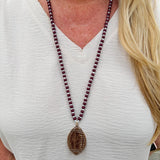 Long beaded necklace with alternating garnet and white beads, featuring a gold football pendant. A bold yet fun Gameday accessory.