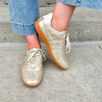 Gold and cream low-top sneaker with subtle metallic sheen, tan sole, and lace-up front—perfect for FSU gameday