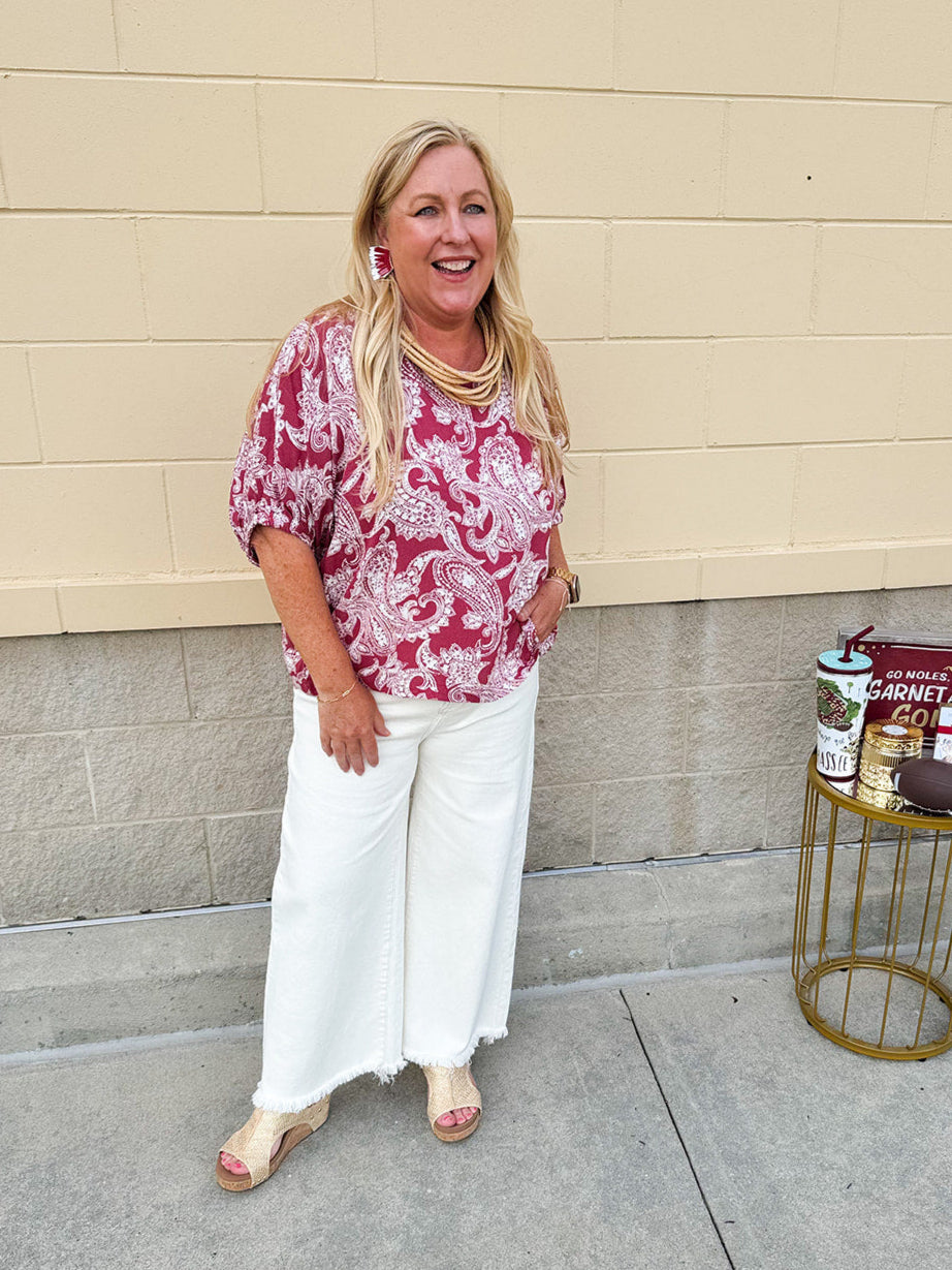 Lightweight garnet top with white paisley print, boat neckline, and loose dolman sleeves.