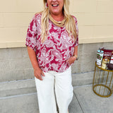 Lightweight garnet top with white paisley print, boat neckline, and loose dolman sleeves.