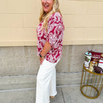 Lightweight garnet top with white paisley print, boat neckline, and loose dolman sleeves.