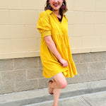Mustard cotton mini dress with a collar, tiered A-line shape, and smocked cuff balloon sleeves—perfect for gameday style.