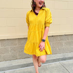 Mustard cotton mini dress with a collar, tiered A-line shape, and smocked cuff balloon sleeves—perfect for gameday style.