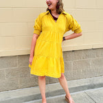 Mustard cotton mini dress with a collar, tiered A-line shape, and smocked cuff balloon sleeves—perfect for gameday style.