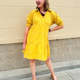 Mustard cotton mini dress with a collar, tiered A-line shape, and smocked cuff balloon sleeves—perfect for gameday style.