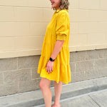 Mustard cotton mini dress with a collar, tiered A-line shape, and smocked cuff balloon sleeves—perfect for gameday style.