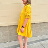 Mustard cotton mini dress with a collar, tiered A-line shape, and smocked cuff balloon sleeves—perfect for gameday style.
