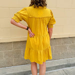Mustard cotton mini dress with a collar, tiered A-line shape, and smocked cuff balloon sleeves—perfect for gameday style.