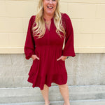 Garnet long sleeve woven mini dress with V-neckline, elastic waist, tiered hem, and pockets—lightweight and perfect for early fall wear
