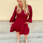 Garnet long sleeve woven mini dress with V-neckline, elastic waist, tiered hem, and pockets—lightweight and perfect for early fall wear