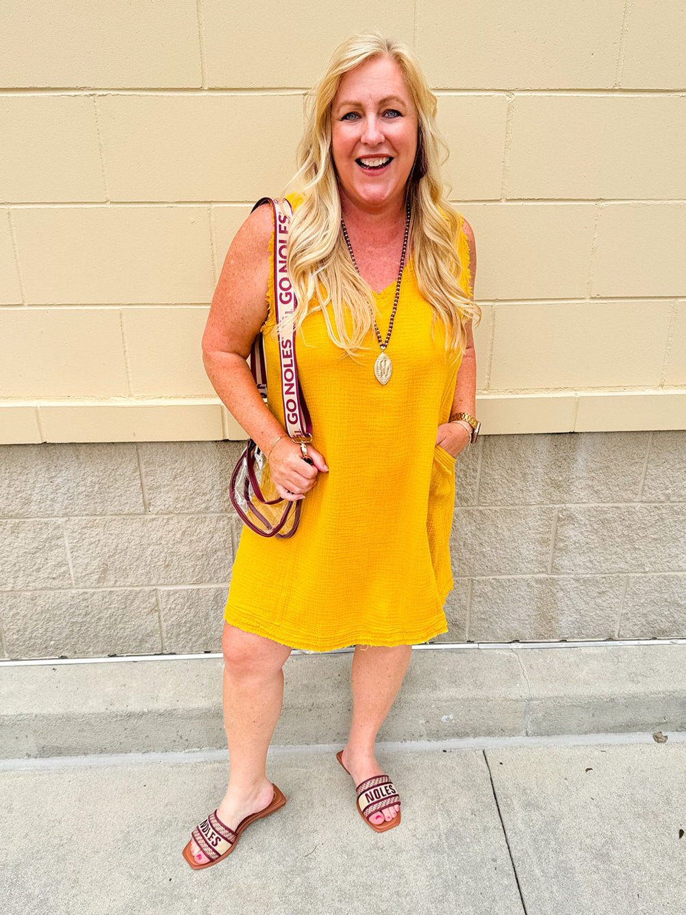 Sleeveless mustard cotton gauze dress with V-neckline, raw frayed edges, and front pockets. Lightweight and casual—ideal for Gameday or fall outings.