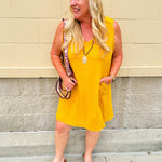 Sleeveless mustard cotton gauze dress with V-neckline, raw frayed edges, and front pockets. Lightweight and casual—ideal for Gameday or fall outings.