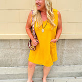 Sleeveless mustard cotton gauze dress with V-neckline, raw frayed edges, and front pockets. Lightweight and casual—ideal for Gameday or fall outings.